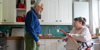 Man and woman using a walker in a kitchen