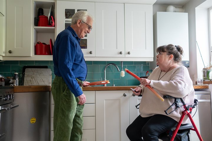 Man and woman using a walker in a kitchen